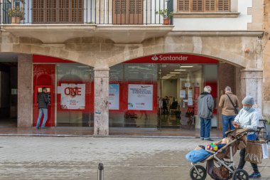 Llucmajor, İspanya; 17 Aralık 2020: Coronavirus 'un aldığı önlemler nedeniyle dışarıda bekleyen yüz maskesi takan müşterileri olan bir İspanyol bankasının cephesi. - Yeni normal