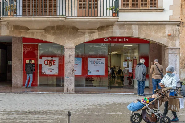 Llucmajor, İspanya; 17 Aralık 2020: Coronavirus 'un aldığı önlemler nedeniyle dışarıda bekleyen yüz maskesi takan müşterileri olan bir İspanyol bankasının cephesi. - Yeni normal