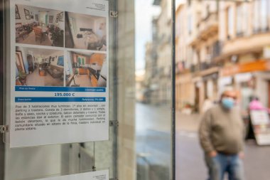 Llucmajor, İspanya; 17 Aralık 2020: bir emlak bürosunun vitrini. Odaklanmamış arka planda sokakta yürüyen bir adam var. Yeni normallik kavramı