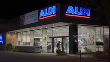 Campos, İspanya; Aralık 2020: Geceleri bir Alman gıda zincirinin süpermarketine giriş. Girişteki müşteriler yemek arabaları ve yüz maskeleriyle çıkıyorlar. Yeni normal