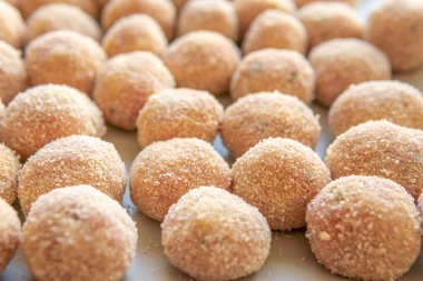 Kare tabakta ekmek kırıntılarıyla kaplanmış köfteler, yağda kızarmadan önce.