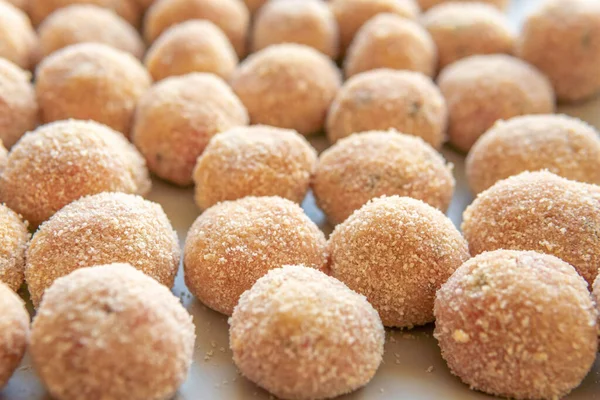 Kare tabakta ekmek kırıntılarıyla kaplanmış köfteler, yağda kızarmadan önce.