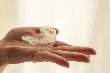 Avucunun içinde diş beyazlatma kalıbı, odak dışında parlak bir arkaplan