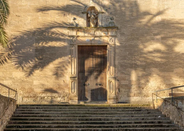 Hıristiyan kilisesi Vilafranca de Bonany 'nin ön cephesinde şafak vakti bir palmiye ağacı projeksiyonu ile
