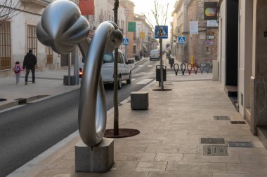 Campos, İspanya; 20 Ocak 2021: Majorcan kasabası Campos 'un ana caddesi, çiçeksel hareketlerin metalik heykeli ve araç ve yayaların dolaşımı
