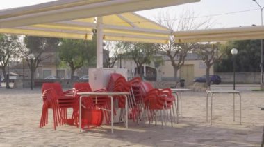 Coronavirus krizinin kapattığı kafeteryanın önüne istiflenmiş kırmızı plastik sandalyeler. Covid-19 tarafından restorasyondaki kısıtlamalar