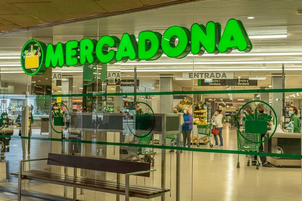 Manacor, İspanya; 18 Mart 2021: İspanyol gıda zincirinin (Mercadona) bir süpermarketinin girişi. İçeride, Coronavirüs salgınından dolayı alışveriş yapan ve maske takan müşteriler var. Yeni normal