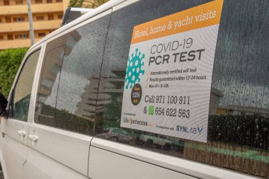 Portals Nous, İspanya; 21 Mart 2021: Kamu yoluna park edilmiş SARS-Cov2 virüsü için PCR ve antijen testi yapan bir şirketin beyaz minibüsü. Yeni normal