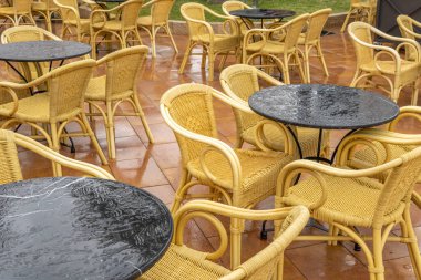 Chairs and tables on the terrace of a restaurant without customers on a rainy day. Image of loneliness and sadness