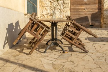 Wooden chairs and tables stacked outdoor. Restaurant businesses closed by Coronavirus crisis