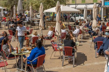 Palma de Mallorca, İspanya; 23 Nisan 2021: Güneşli bir sabahta Palma de Mallorca 'nın tarihi merkezinde bir kafeteryanın terası, müşteriler ve işçiler yüz maskesi takıyor, çünkü Coronavirus