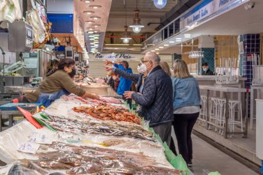 Palma de Mallorca, İspanya; 23 Nisan 2021: Alışverişçiler ve satıcılar geleneksel Mercado del Olivar 'da bir balık pazarında yüz maskesi takıyorlar. Covid-19 salgını sırasında yeni normallik