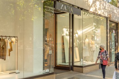 Palma de Mallorca, Spain; april 23 2021: Shop window of a clothing and accessories store belonging to the multinational Zara, with people wearing face masks due to the Coronavirus pandemic. New normal