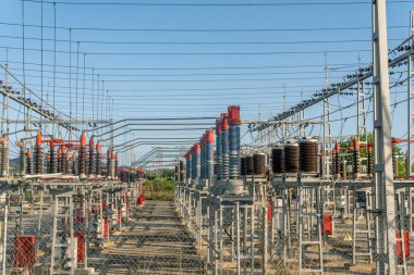 Gün batımında güneşli bir tarlanın ortasında bir enerji santralinin metalik kuleleri