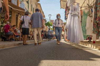 Campos, İspanya; 12 Haziran 2021: Majorcan 'ın Campos kasabasındaki haftalık sokak pazarında kıyafet tezgahları. Yüz maskesi takan insanlar. Koronavirüs salgını. Yeni normallik kavramı