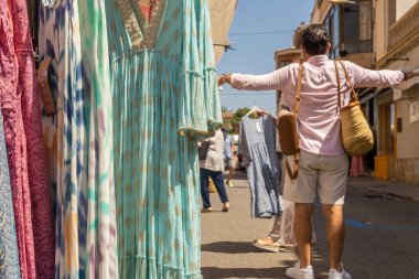 Majorcan kasabası Campos 'taki haftalık sokak pazarındaki bir giyim mağazasının yakın çekimi. Odak dışı, insanlar yüz maskesi takarak yürüyorlar. Koronavirüs salgını. Yeni normallik kavramı