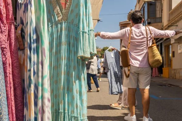 Majorcan kasabası Campos 'taki haftalık sokak pazarındaki bir giyim mağazasının yakın çekimi. Odak dışı, insanlar yüz maskesi takarak yürüyorlar. Koronavirüs salgını. Yeni normallik kavramı