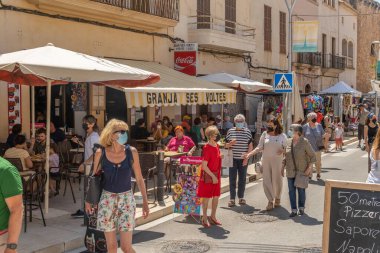 Campos, İspanya; 12 Haziran 2021: Majorcan 'ın Campos kasabasındaki haftalık sokak pazarında kıyafet tezgahları. Yüz maskesi takan insanlar. Koronavirüs salgını. Yeni normallik kavramı
