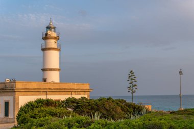 Yazın gün batımında Mallorcan 'ın Ses Salines kasabasının deniz feneri. Altın saat