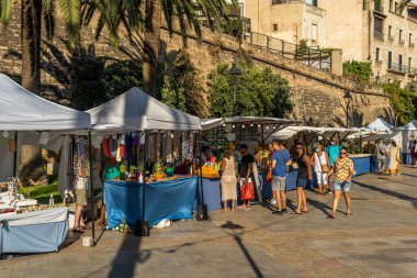 Palma de Mallorca, İspanya; 10 Eylül 2021: Palma de Mallorca kentindeki gezinti alanında el sanatları satan turizm pazarı, gün batımında insanların bakınıp alışveriş yaptığı yerler