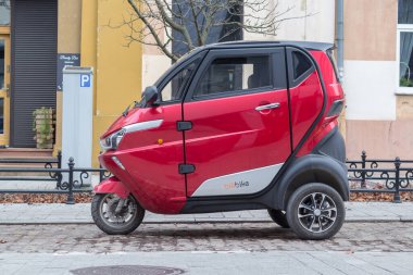 Şehrin caddesinde park etmiş kırmızı üç tekerlekli scooter..