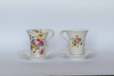 Beyaz arka planda fincan tabakları olan zarif çiçek porselenleri..