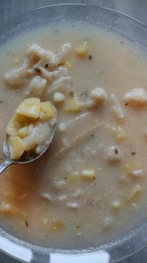 Ev yapımı karnabahar çorbası, kaşıkta patates ve cam tabak..