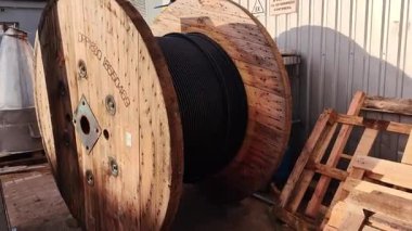 Büyük ahşap kablo varili, dışarıda sarmalanmış endüstriyel güç kablosu var..