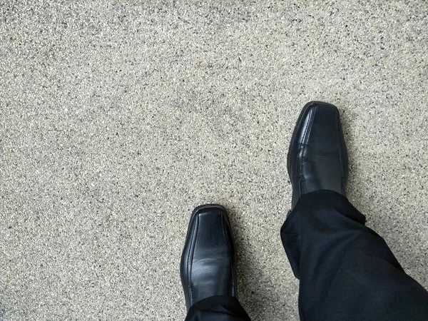 Concept of go to your goal, which is compared to walking the desired pathway. Asian man is walking on the rough floor and wear black shoes and black slack pants.