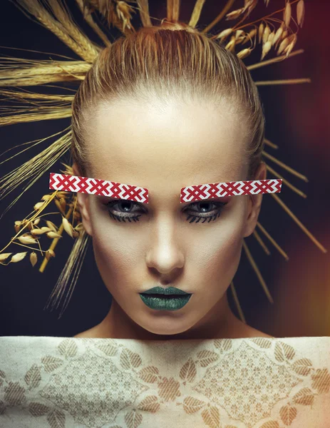 Fashion portrait of a girl with ears in her hair and the national pattern of the eyebrows and towel — Stock Photo, Image