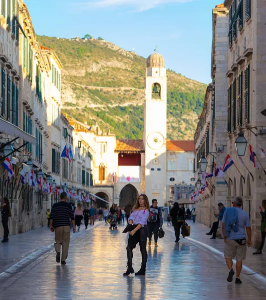 Dubrovnik Hırvatistan Kasım 2020 'de eski Dubrovnik kasabasındaki Stradun Caddesi' nin ortasında duran Brunette, çok sayıda kişinin geçtiği pozunu verdi. Covid mevsiminde sonbaharda yürüyen turistler