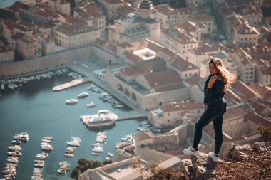 Çekici esmer, Dubrovnik şehrinin üzerinde duran bir kayanın kenarında duruyor. Görkemli antik şehrin üzerinde güzel altın saat, sonbaharda gezginler bölgeyi ziyaret ediyor.