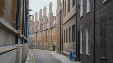 Cambridge UK Ocak 2021 Cambridge caddesindeki ünlü Trinity Sokağı 'nda koşan bir kişi. Soğuk bir kış gününde bacası olan güzel kahverengi uzun evler.
