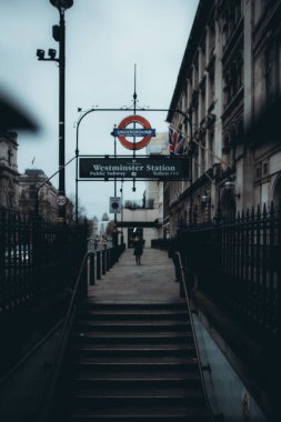 Londra İngiltere Ocak 2021 Westminster metro istasyonuna giriş. Soğuk kış günü, arka planda sendika bayrağı. Ulusal tecrit sırasında kırmızı çift katlı otobüsler geçiyor