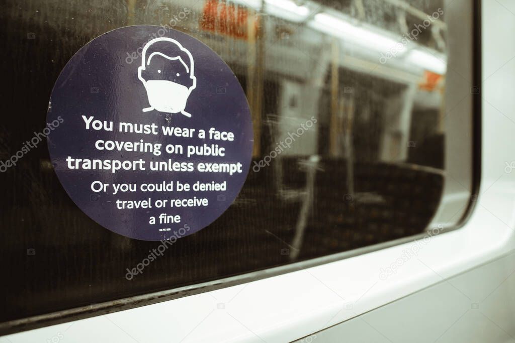 Text sign on an English train stating that a mask has to be worn on pubic transport or a fine will be received. Trains empty during UKs national covid lockdown
