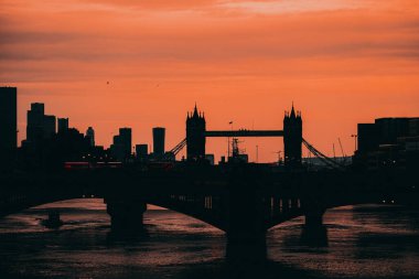 Londra Birleşik Devletleri Şubat 2021 öğleden sonra Thames nehri üzerinde kış günbatımı, arka planda Tower Köprüsü 'nün ana hatları. Ön planda köprüden geçen çift katlı otobüsler