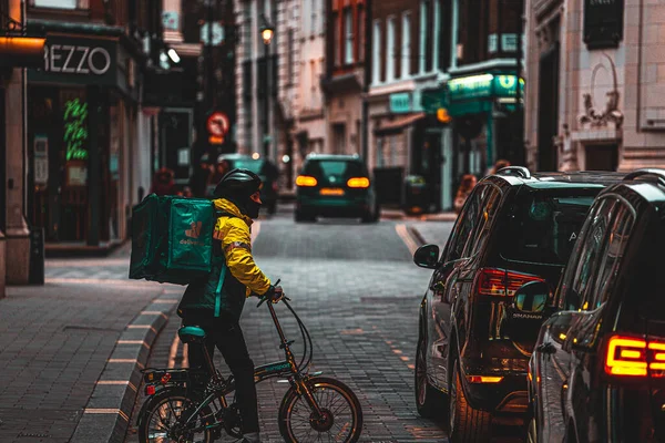 Londra İngiltere Şubat 2021 'de Tek Başına, bisikletle trafik sıkışıklığından geçmeye çalışan ve gece geç saatlerde UKs tecrit sırasında bisikletini arabaların arasına iten yemek dağıtım elemanı.