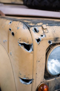 Çölün kamuflaj renklerine boyanmış sarı bir aracın önünde kurşun ve şarapnel delikleri var. Modern çatışma kavramları ve gazeteciler ve gazeteciler için tehdit