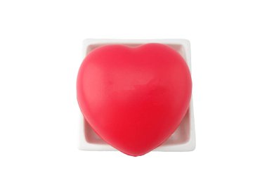 Beyaz kare seramik tabakta kırmızı, şirin bir kalp. Kırpma yolu olan beyaz arka planda izole edilmiş. Sevgililer Günü konseptinde aşkın işareti.