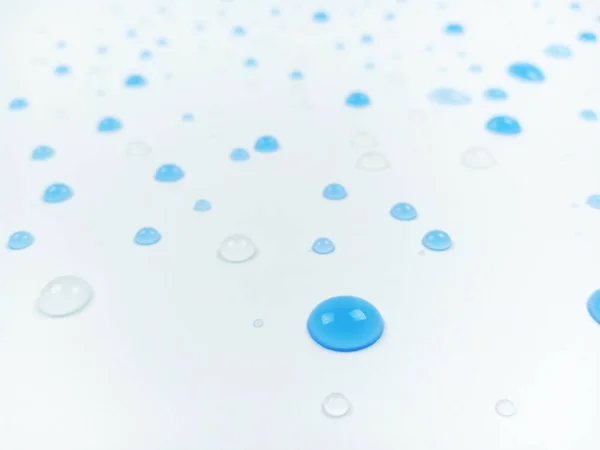 青と澄んだ水の選択的な焦点は ぼやけた効果で白い背景に落ちます — ストック写真
