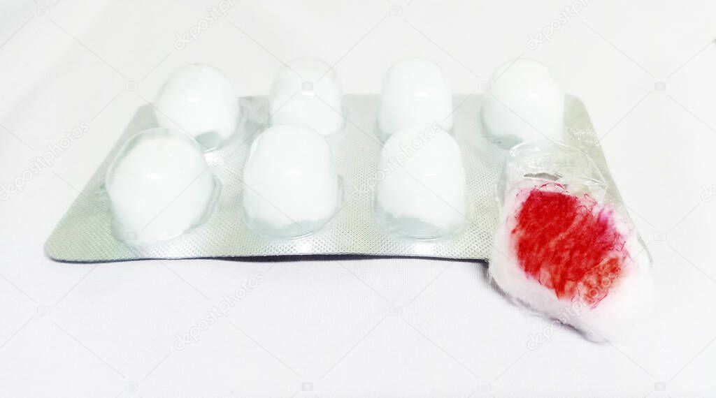 Sterile alcohol cotton ball panel with one stained with blood on white background.