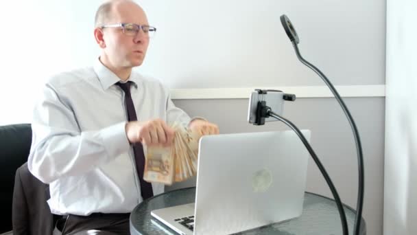 Egy kaukázusi férfi ül egy laptopnál, sok pénze van és boldog.. — Stock videók