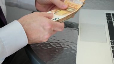 Beyaz bir adam internetten para kazandı. Avro banknotlarını sayar.