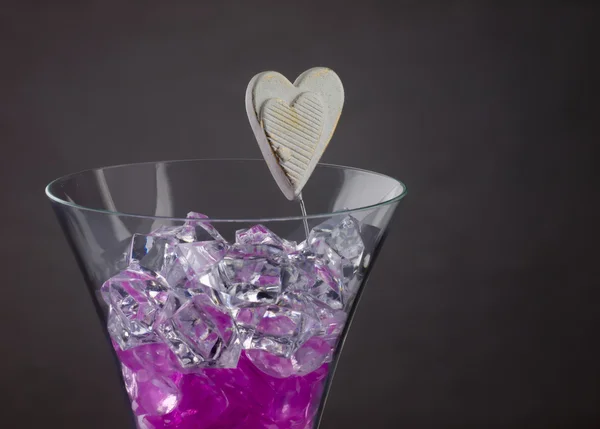 Copo de champanhe cheio de corações roxos e cristais de gelo . — Fotografia de Stock