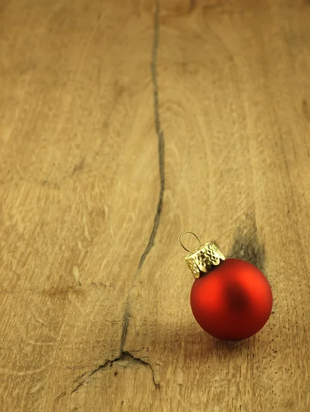 Bauble rosso di Natale su uno sfondo di legno di quercia . — Foto Stock