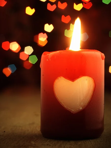 Red candle on the table and shiny hearts in background. — Stock Photo, Image