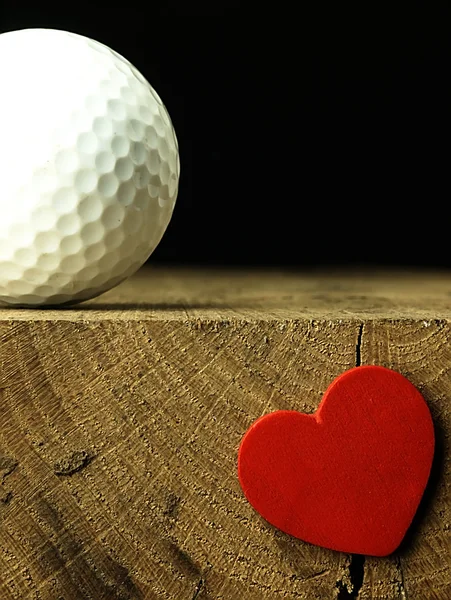 Pallina da golf e cuore sul bordo del tavolo . — Foto Stock