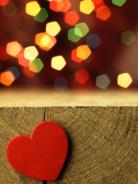 Corazón rojo en el borde de una mesa de madera . — Foto de Stock