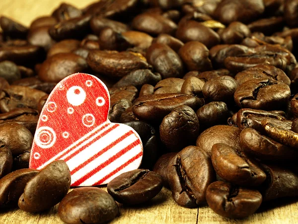 Coração e grãos de café close-up em madeira, mesa de carvalho . — Fotografia de Stock