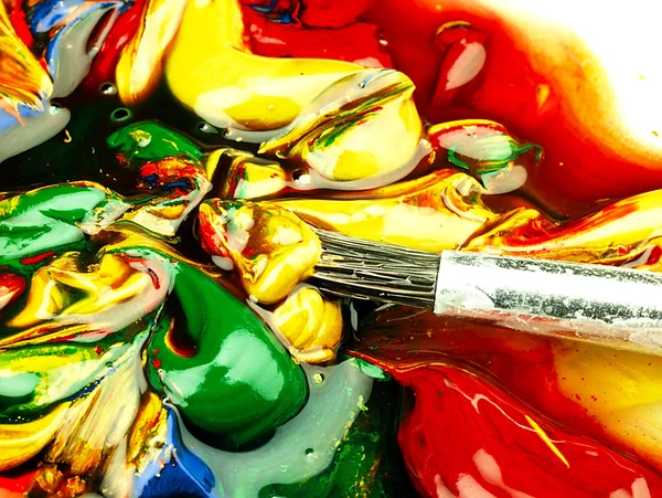 Pittura colorata mista su tavolozza. Spazzola sporca in primo piano . — Foto Stock